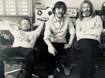 De tre bandmedlemmene som sitter sammen i studio